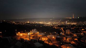 A nighttime view of a city with illuminated buildings and a prominent tower in the distance.