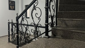 Una escalera con barandillas de metal negro ornamentado y piso de granito.