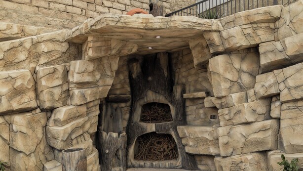 Un arco de piedra con un interior rústico, similar a una cueva, que conduce a un nivel inferior.