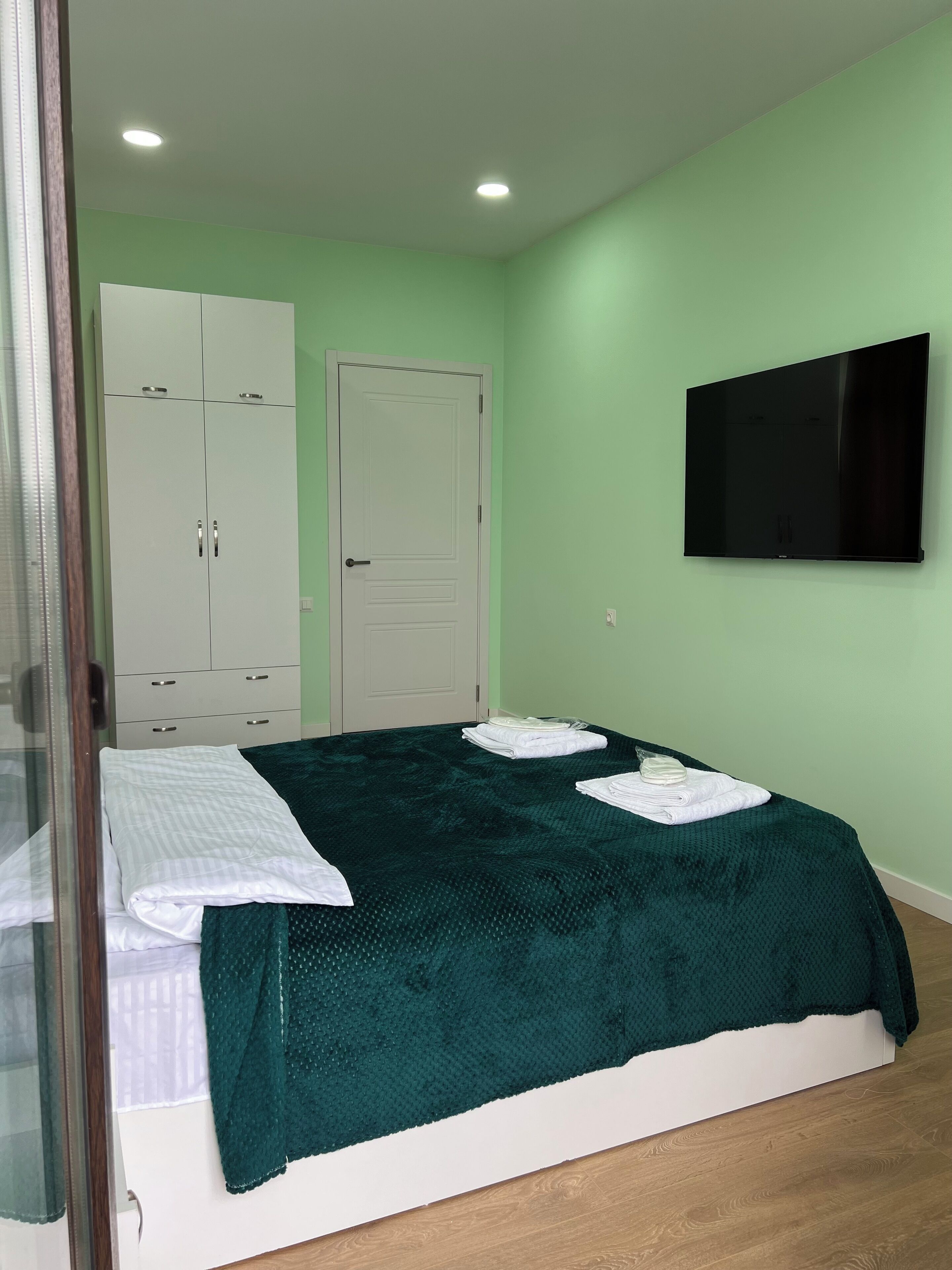 Ein Schlafzimmer mit einem Bett, einem Kleiderschrank, einem Fernseher und einer Tür.