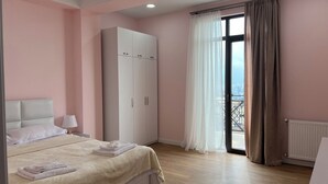 Un dormitorio con cama, armario, ventana con cortinas y radiador.