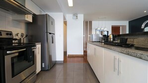 A modern kitchen with stainless steel appliances, white cabinetry, and a granite countertop. - w* | Classy 2BR in Miraflores (Miraflores)