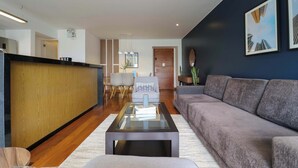 A modern living room with a sofa, a coffee table, and a dining area with chairs. - w* | Classy 2BR in Miraflores (Miraflores)