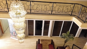 A spacious balcony with a modern railing, a chandelier, and a seating area with sofas and a coffee table. - Dreamland suites (Abuja)