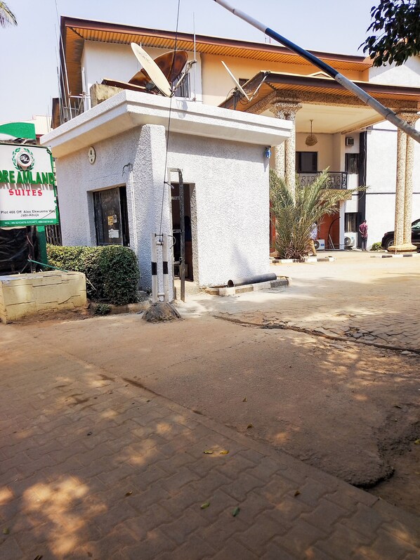 A building with a sign for Dreamland Suites, a satellite dish, and a paved entrance area. - Dreamland suites (Abuja)