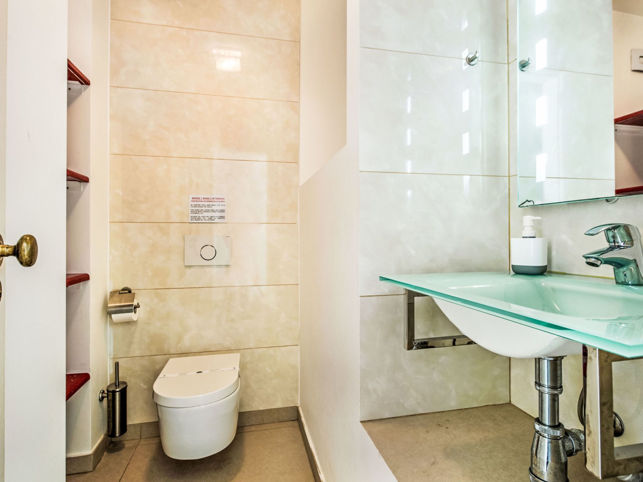 A modern bathroom with a glass sink, a toilet, and a mirror.