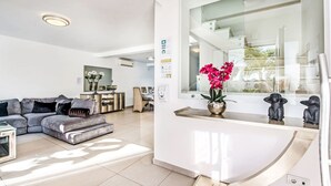 Una sala moderna con un sofá modular, un comedor y un ventanal con vistas al exterior.