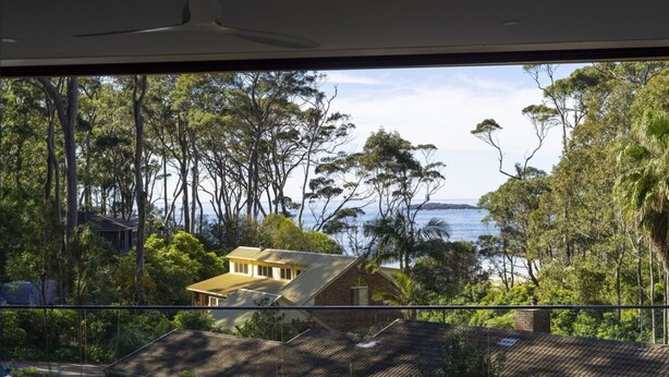 Une propriété située sur la côte, offrant une vue sur la mer et entourée d’une forêt dense.