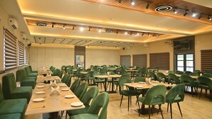Ett rymligt konferensrum med grönt klädda stolar och bord, utrustat med takbelysning och ventilationssystem.