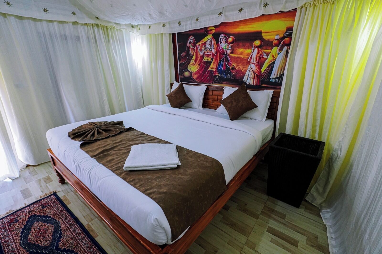 A neatly made bed with white and brown linens, a folded towel, and a decorative brown cloth.