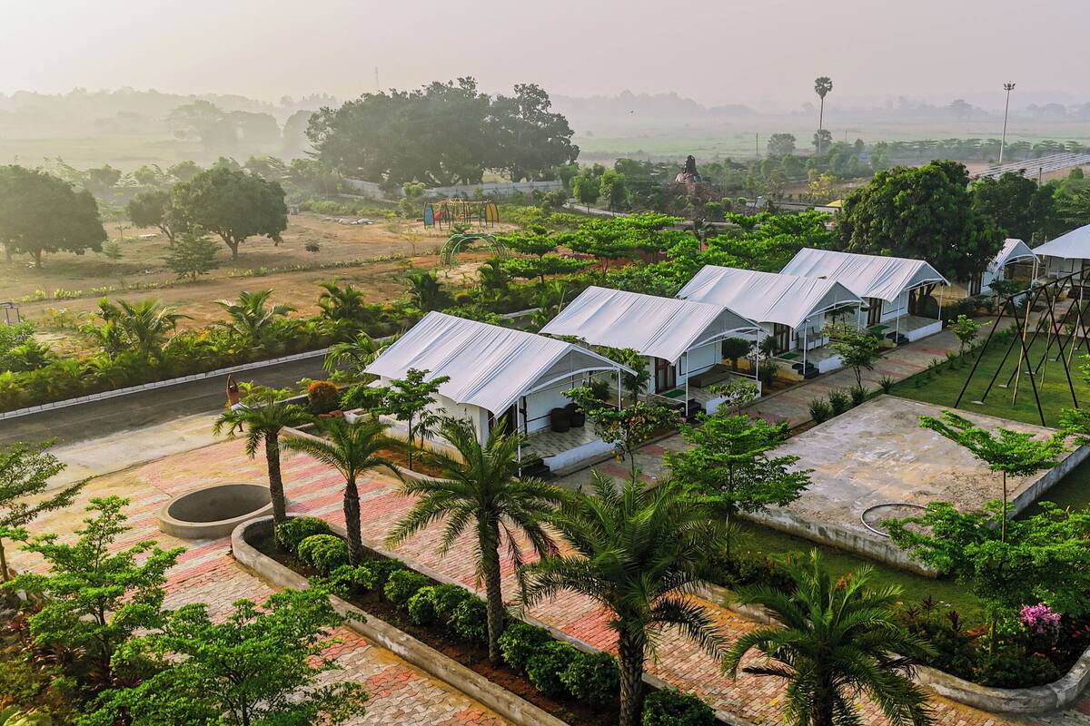 A row of white-roofed cottages with a paved walkway and palm trees in the foreground.