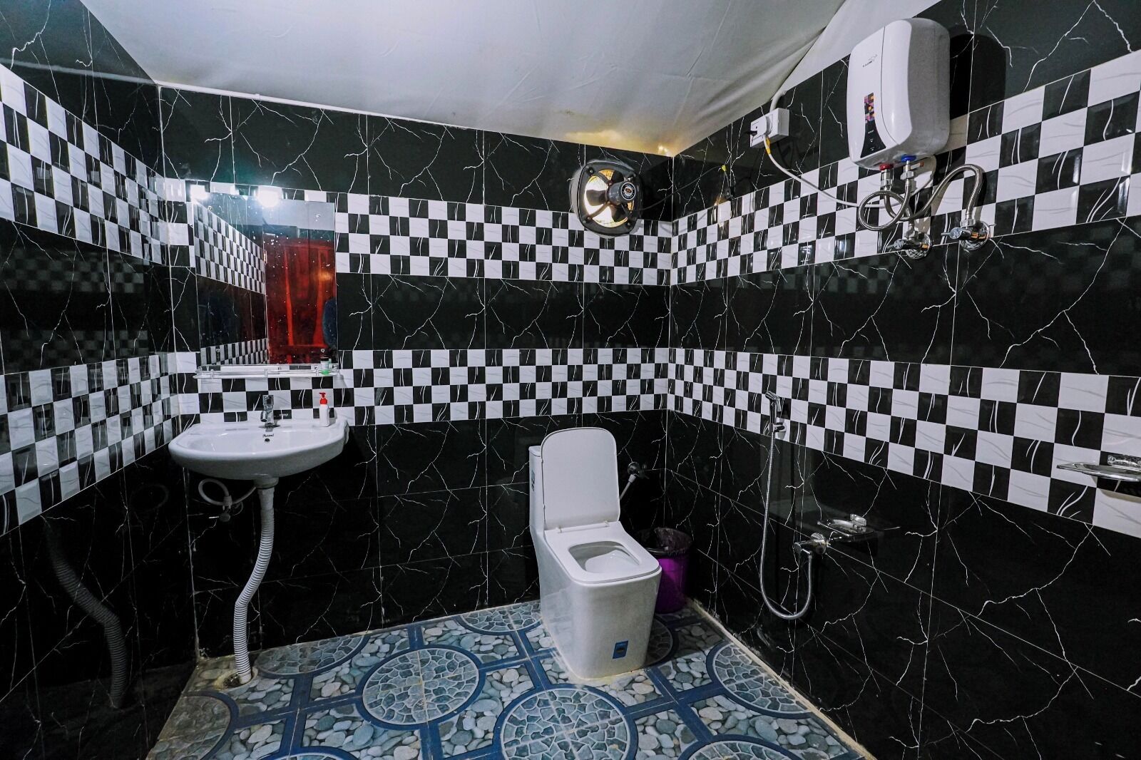 A bathroom with a checkered black and white tile pattern, a white sink, a toilet, and a shower area.