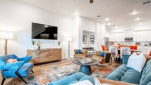 A modern living room with a sofa, chairs, a coffee table, and a TV mounted on the wall. - Game Day Home Base | Steps to Globe Life & AT&T (Arlington)
