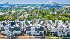 A residential area with modern apartment buildings, a stadium, and surrounding greenery. - Game Day Home Base | Steps to Globe Life & AT&T (Arlington)