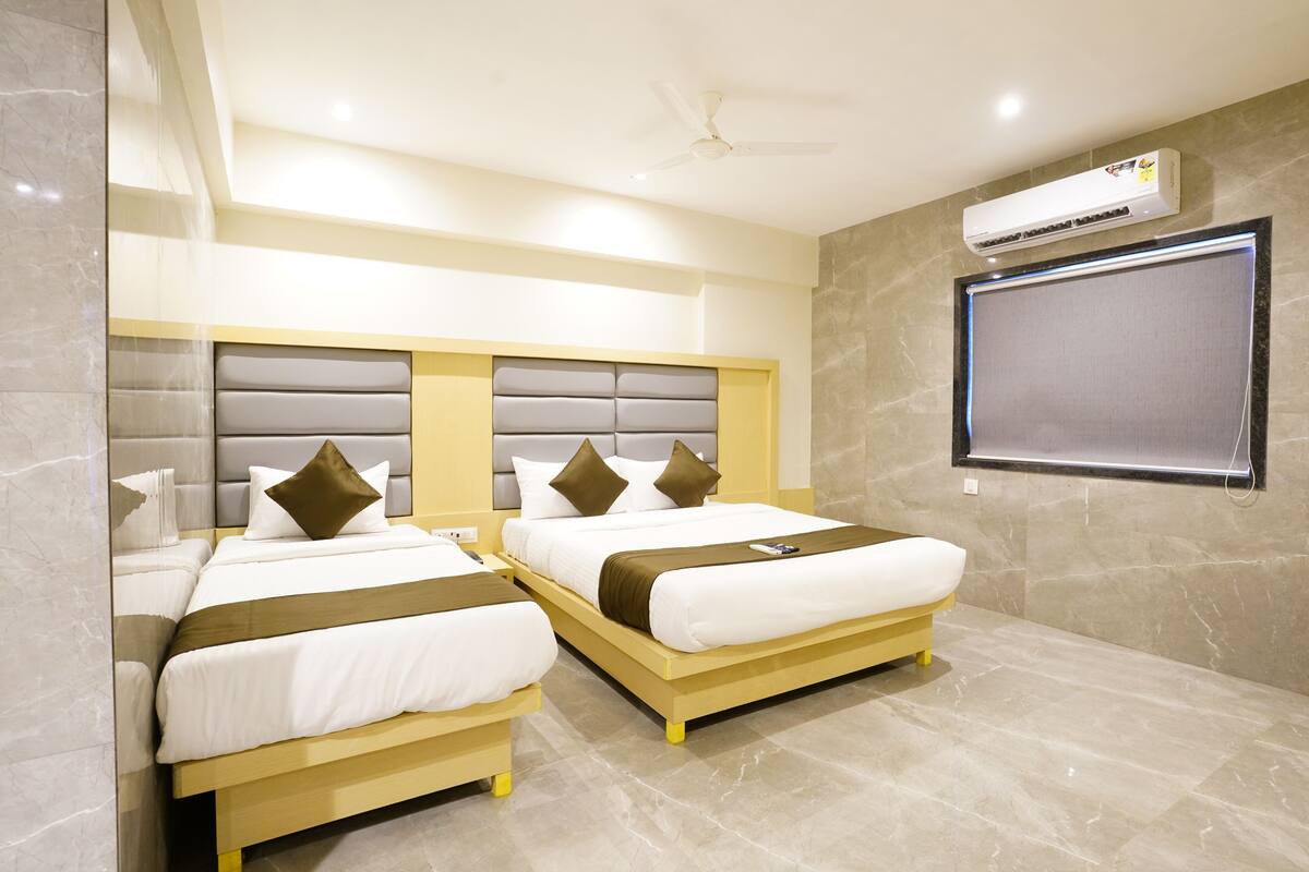 A hotel room with two beds, a ceiling fan, an air conditioning unit, and a large window.