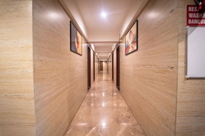A hallway with wooden paneling and marble flooring, leading to a door at the end.