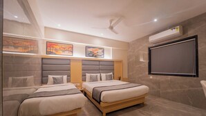 Ein modernes Schlafzimmer mit zwei Betten, einem Deckenventilator und Bildern an den Wänden.