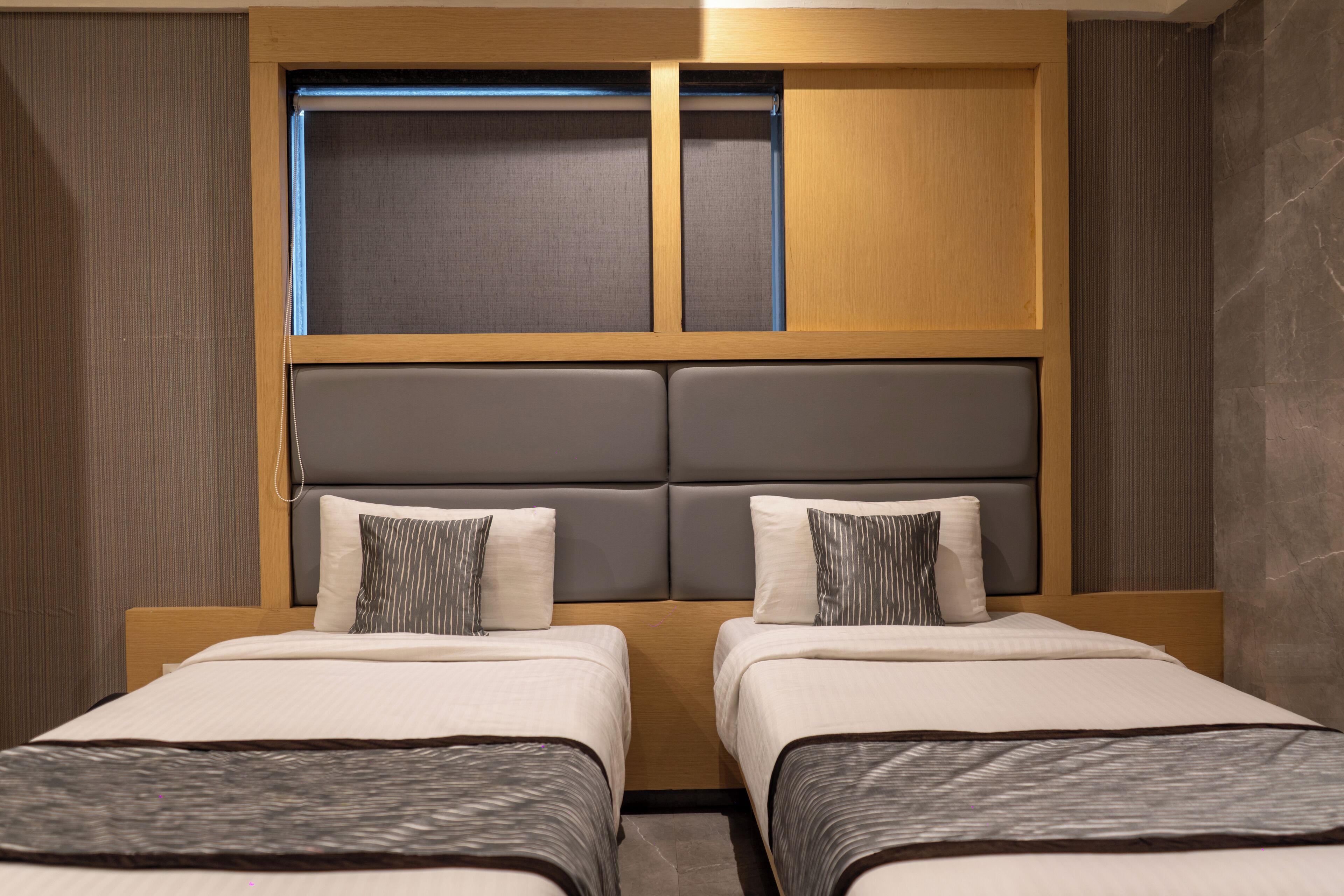 A hotel room with two beds, a large window, and a modern design.