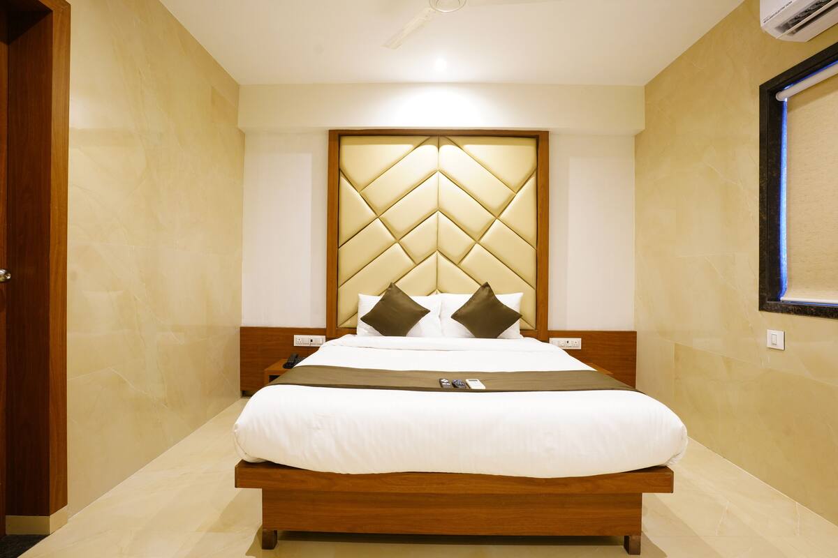A hotel room with a large bed, wooden headboard, and a modern design.
