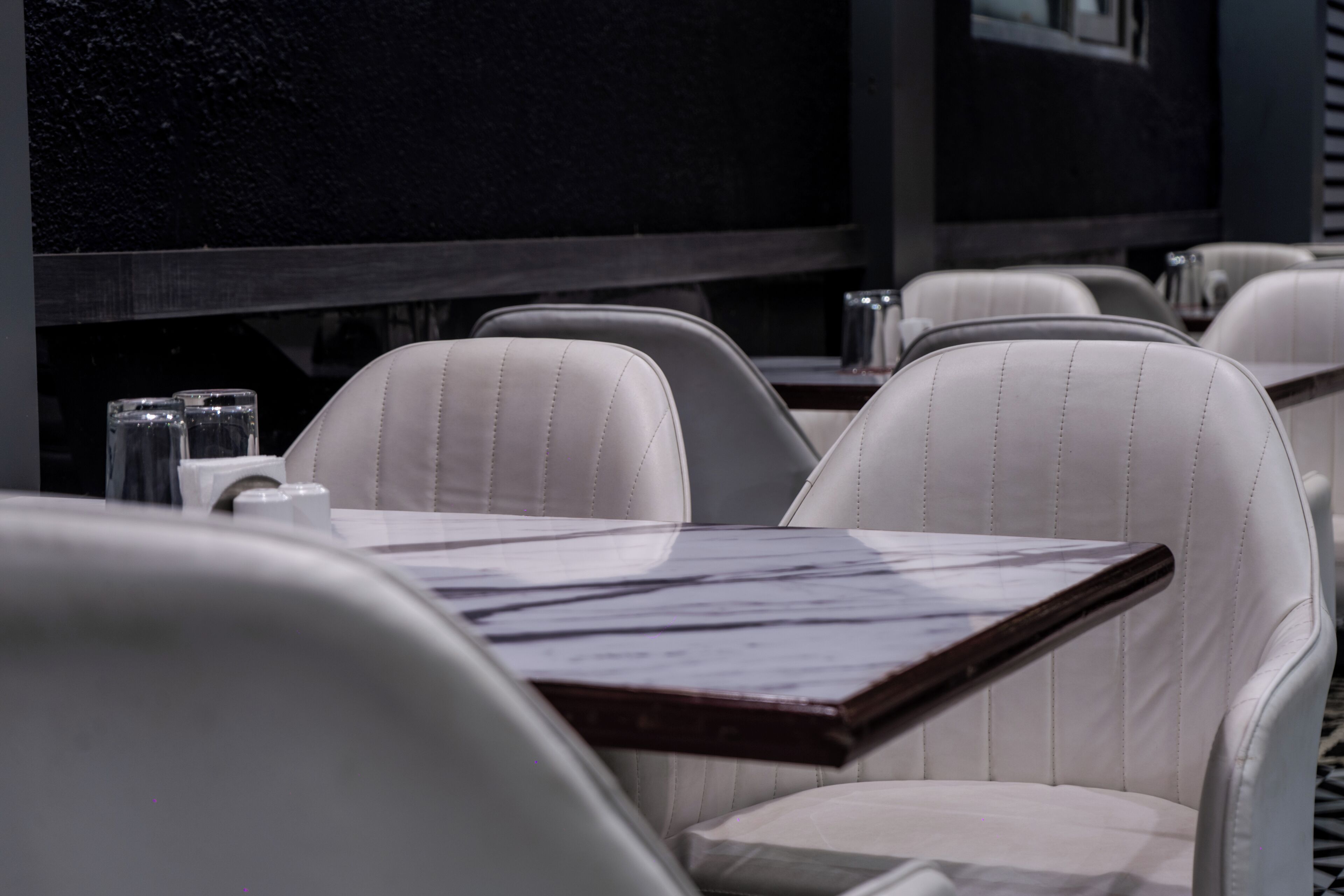 A restaurant interior with white leather chairs and a dark wooden table.