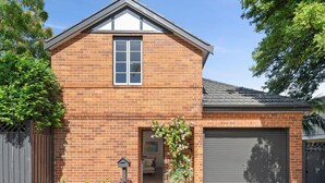 A two-story brick house with a garage, a front door, and a large potted plant. - Reed Cottage - Large private garden cottage a perfect base for your Sydney stay (Cremorne)