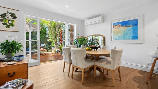 A dining area with a wooden table and chairs, a potted plant, and a view of the outdoors. - Reed Cottage - Large private garden cottage a perfect base for your Sydney stay (Cremorne)