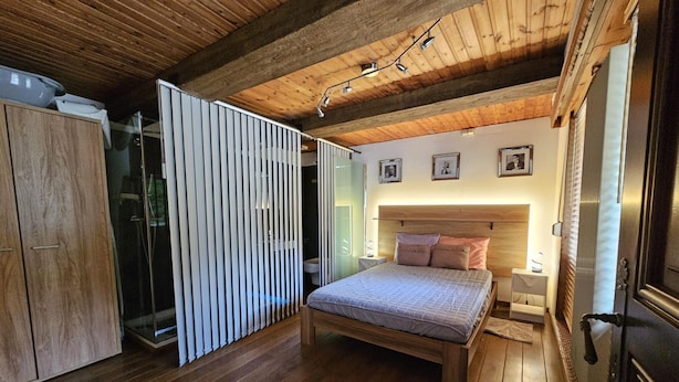 A bedroom with a wooden bed, a wardrobe, a glass partition, and a wooden ceiling. - Farmhouse in Belgium With Lush Garden Retreat (Hastiere)