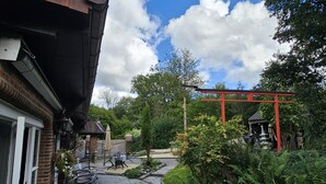A stone pathway leading to a red pergola in a garden setting. - Farmhouse in Belgium With Lush Garden Retreat (Hastiere)
