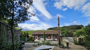 A rustic building with a gravel patio, a stone bench, and a small garden area with a tree and a stone sculpture. - Farmhouse in Belgium With Lush Garden Retreat (Hastiere)