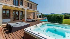 A stone house with a pool, outdoor seating, and a hot tub.