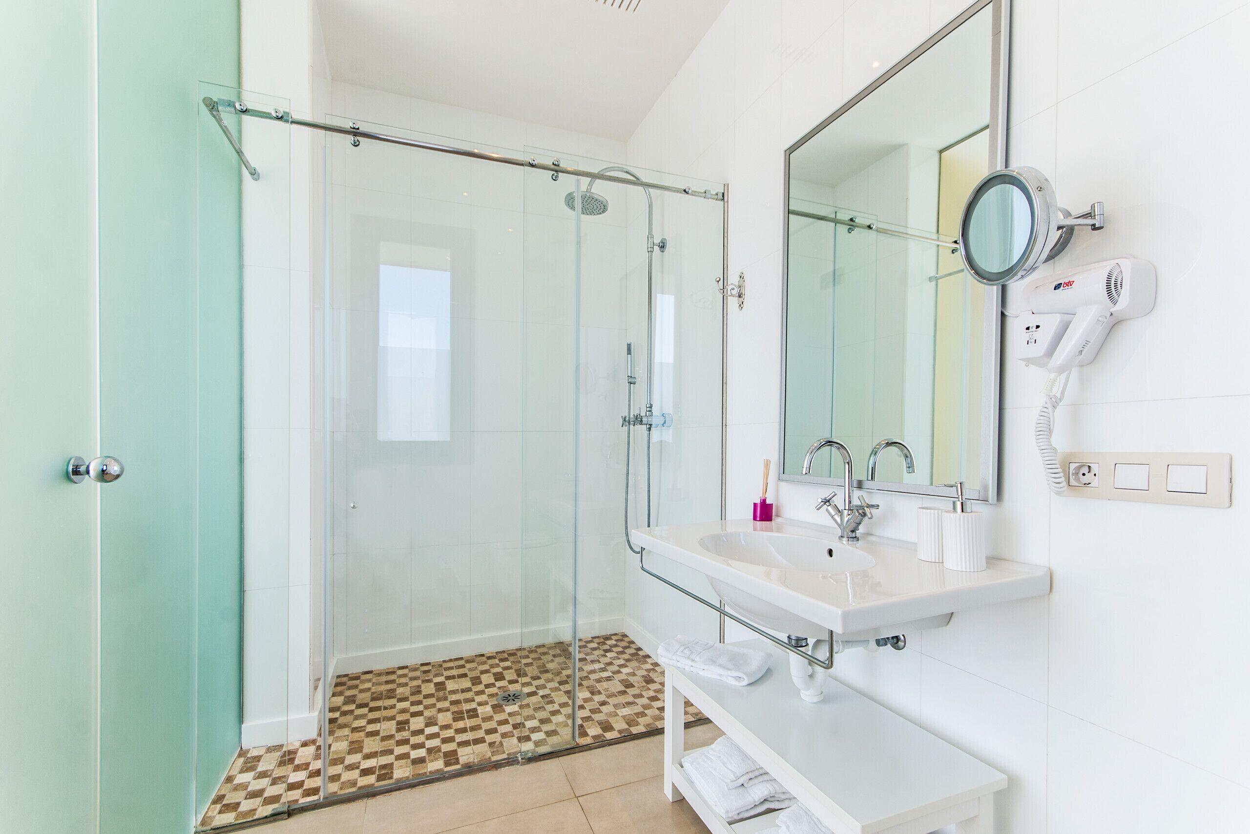 Une salle de bain moderne avec une douche à parois de verre, un lavabo blanc et un grand miroir.