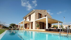 A modern house with a swimming pool, outdoor seating, and a covered patio area.