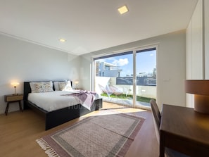 Ein modernes Schlafzimmer mit Bett, Nachttischen, einem großen Fenster und Blick ins Freie.