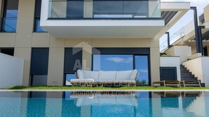 Una casa moderna con piscina, un sofá blanco y una escalera.