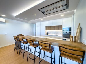 Una cocina moderna con una isla central, taburetes de bar y un ventanal grande.