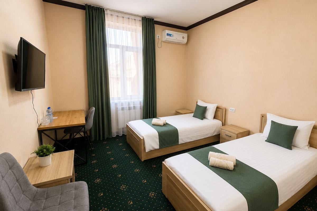Une chambre d’hôtel avec deux lits, un bureau, une chaise, un téléviseur et un appareil de climatisation.