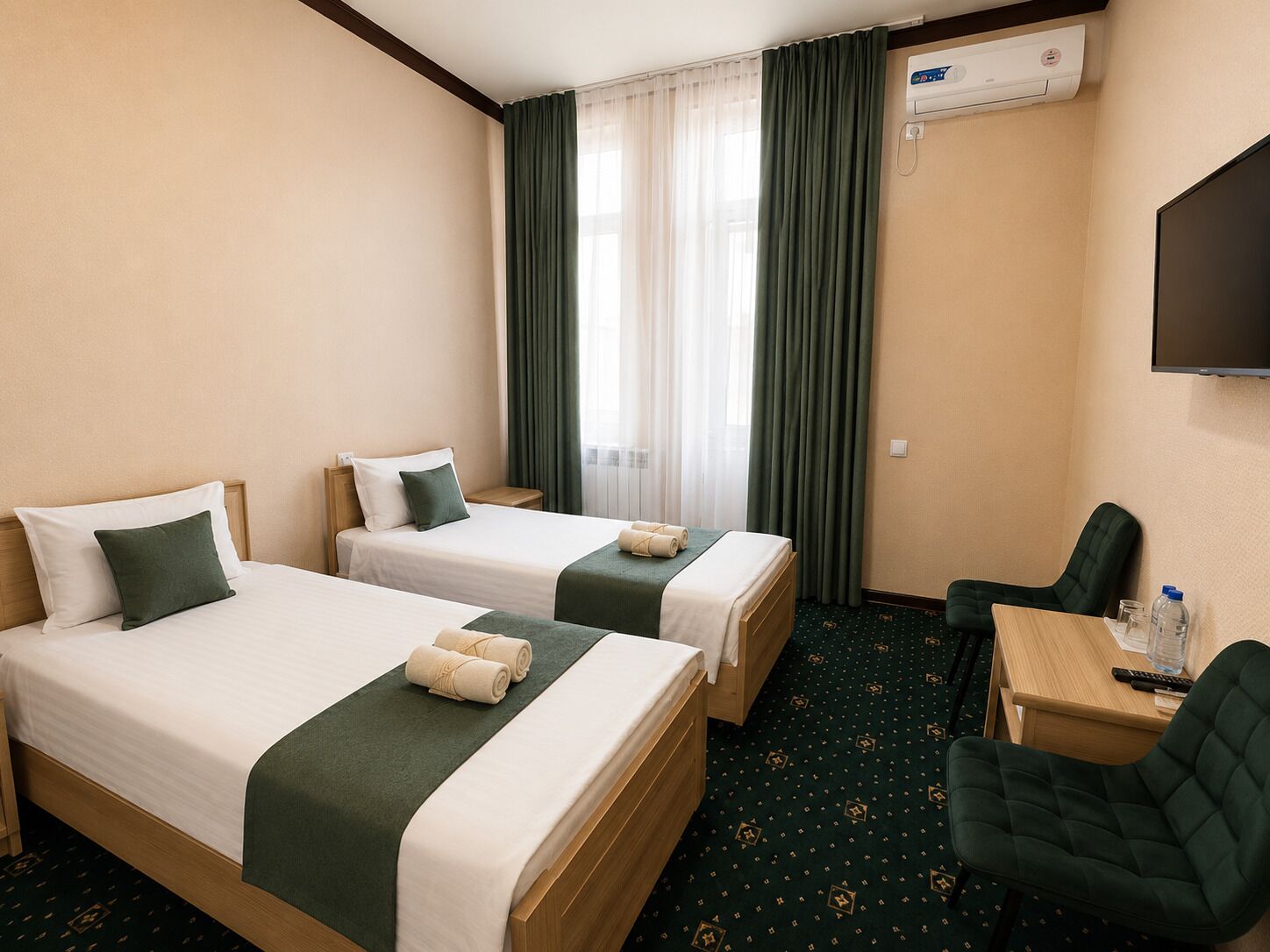 Ein Hotelzimmer mit zwei Betten, einem Schreibtisch, einem Sessel, einer Klimaanlage und einem Fernseher.
