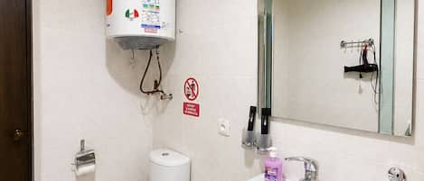 Une salle de bain équipée de toilettes, d’un lavabo, d’un miroir et d’un chauffe-eau.