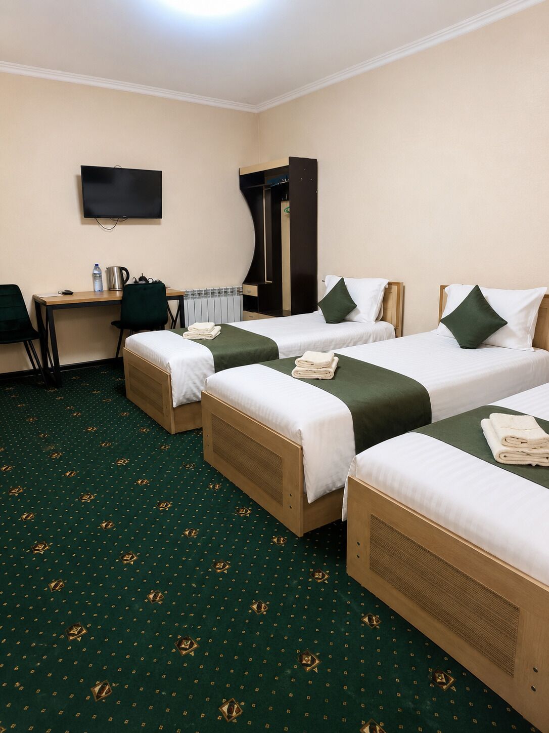 Camera d'albergo con due letti, una scrivania, una sedia, un televisore e un termosifone.