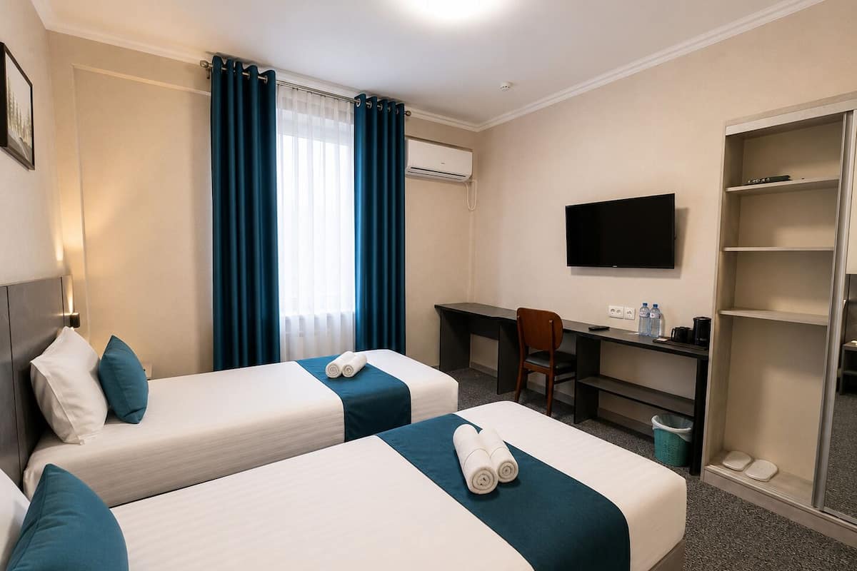 Une chambre d’hôtel avec deux lits, un bureau, une chaise, une télévision et une armoire.