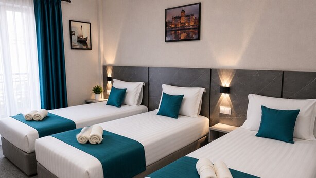 A hotel room with three single beds, each with a teal bedspread and white pillows, a nightstand with a lamp, and a framed picture on the wall. - BOSTON HOTEL (Tashkent)