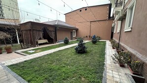 A courtyard with a paved pathway, small trees, and potted plants. - BOSTON HOTEL (Tashkent)