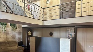 A room with a large flat-screen TV, a sofa, a clock, and a staircase. - BOSTON HOTEL (Tashkent)