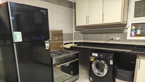 Uma cozinha compacta com geladeira preta, fogão e máquina de lavar.