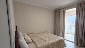 Quarto com cama, cortinas e vista para o exterior.