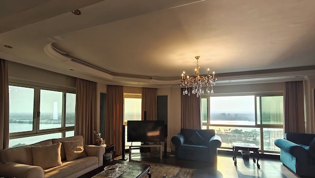 Uma sala de estar espaçosa, com uma televisão grande, dois sofás, uma mesa de centro e um candelabro.