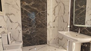 Casa de banho com chão de mármore, lavatório branco e espelho.