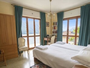 A hotel room with two beds, a desk, a chair, a bookshelf, and large windows with a view of mountains. - Beautiful apartment for 6 guests with WIFI, TV, balcony and pets allowed (San Mamete)