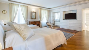 Um quarto espaçoso com uma cama grande, televisão, penteadeira e uma cadeira.