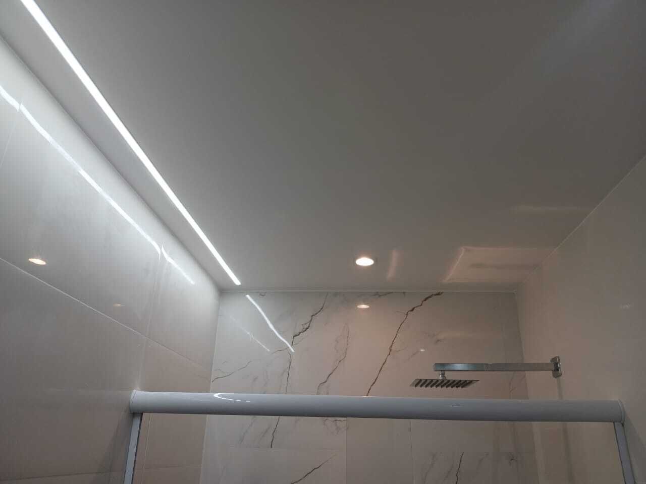 Un bagno moderno con pareti in marmo bianco e box doccia in vetro.